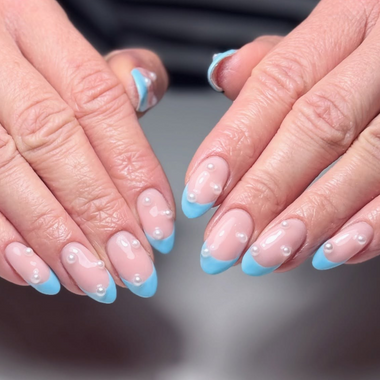 Close-up of two sets of hands with blue and clear nail polish on a blurred background